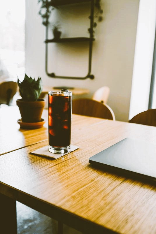 A table with a cold drink and a closed laptop.